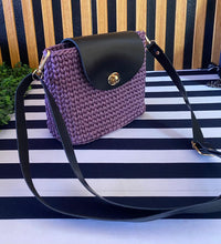 Load image into Gallery viewer, Purple woven handbag with black leather accents on a striped background
