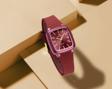 Load image into Gallery viewer, Maroon watch with gold accents on a beige background
